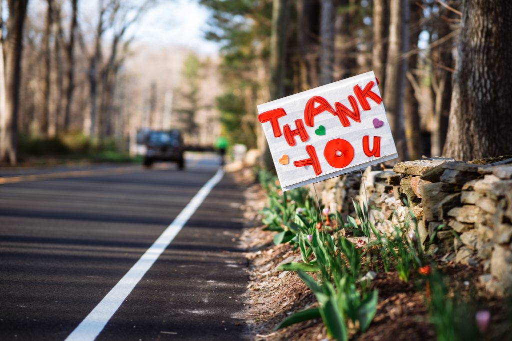 a thank you sign planted by the side of a road